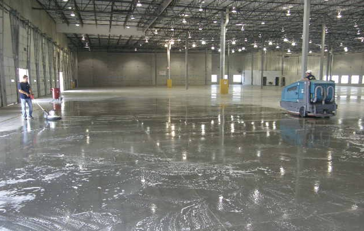 Professional pressure washing a warehouse floor in protective gear